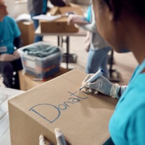 Close-up of woman marking donation boxes while volunteering at charity center.