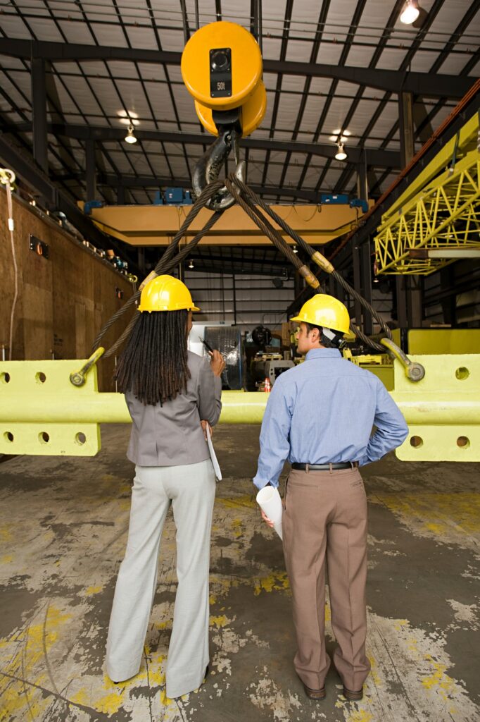 Two construction professionals inspecting machinery at an industrial site.